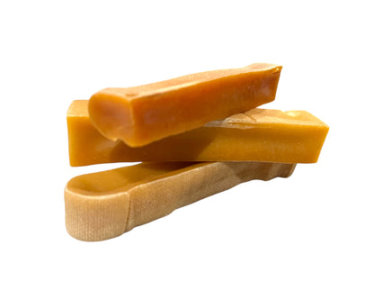 Three large rectangular dog chews, made out of dehydrated cheese curds, placed on top of the other.